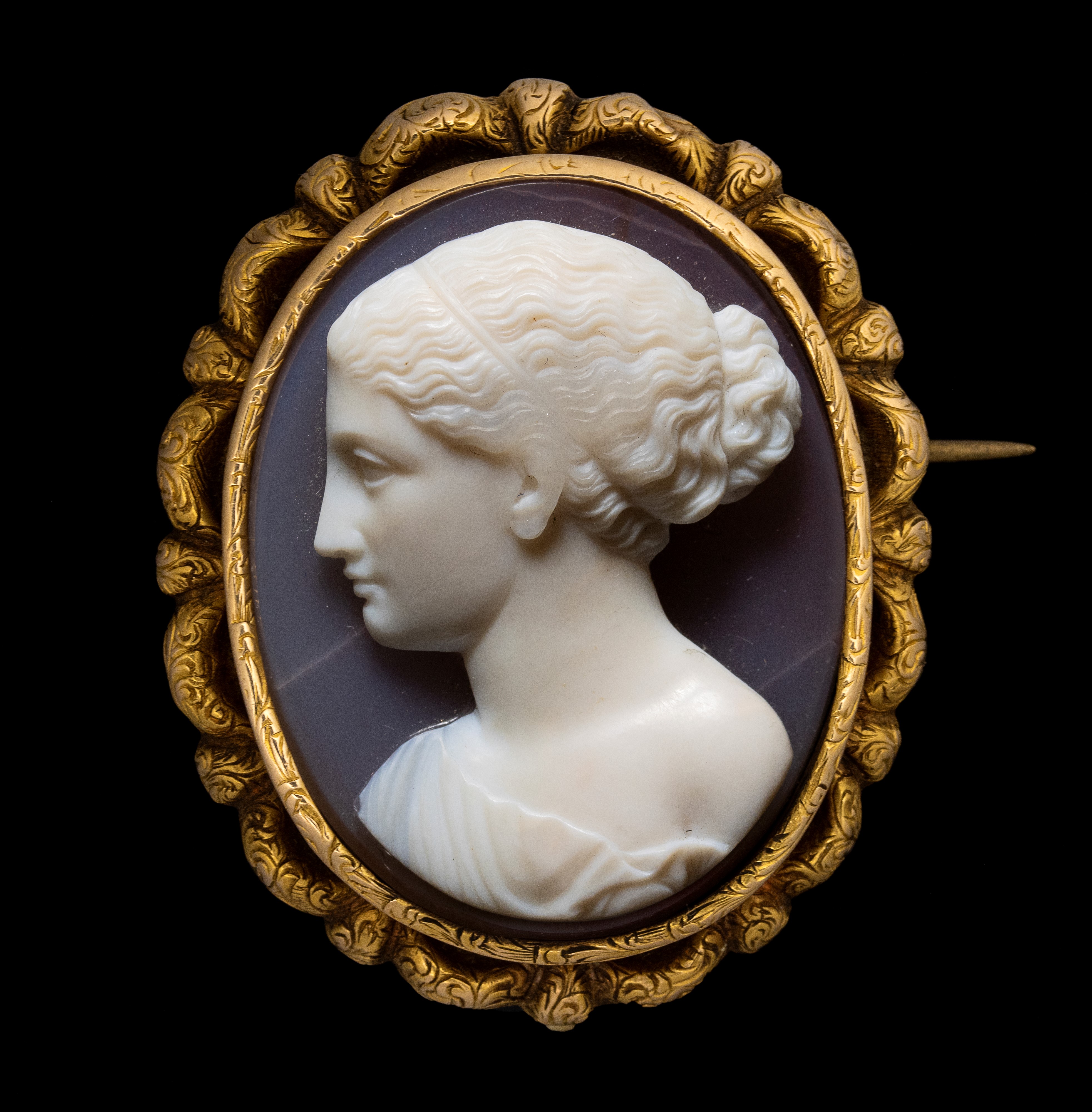 A fine Neoclassical agate cameo set in a gold chiseled brooch. Female bust.