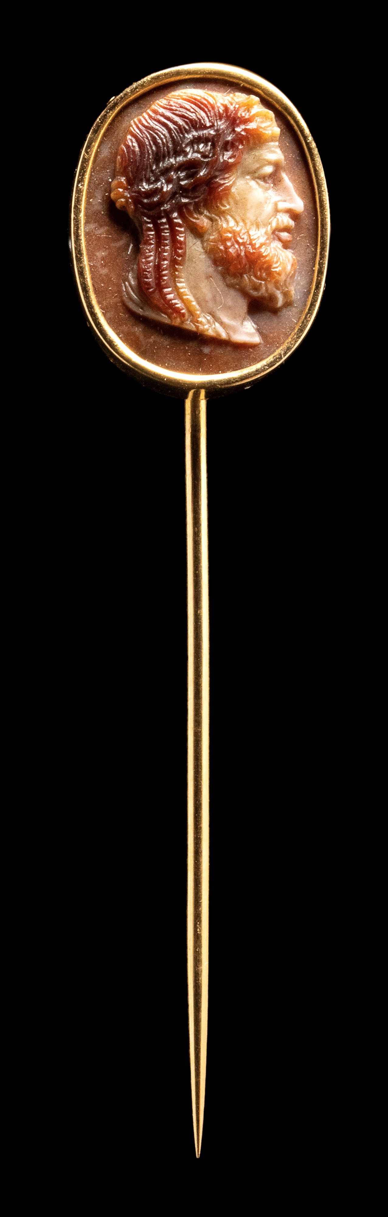 A three-layered agate cameo set in a gold stick pin. Bust of Zeus.