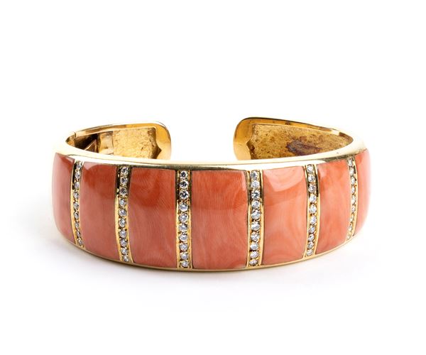 A gold open bangle bracelet featuring an elegant blend of coral and diamonds  